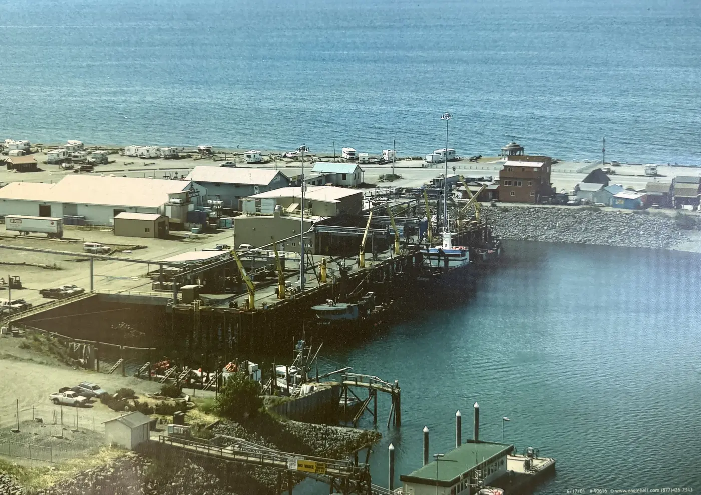Vintage photo of a vessel tied up at the Homer Spit dock, cranes working the offload